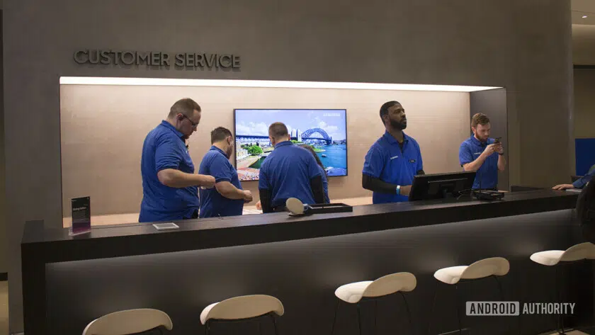 Samsung employees standing behind the counter at the customer service section of the Samsung Experience Store in Long Island.