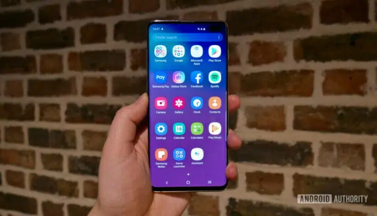 Photo of a Samsung Galaxy S10 held in a hand showing the One UI app drawer.