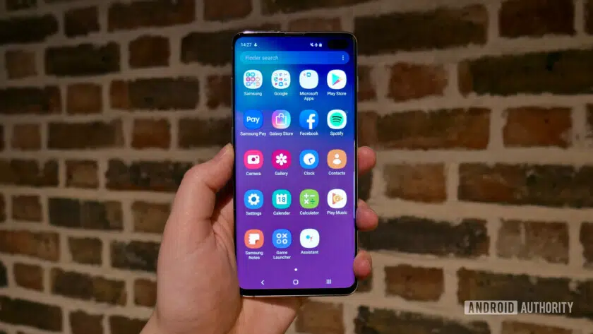 Photo of a Samsung Galaxy S10 held in a hand showing the One UI app drawer.