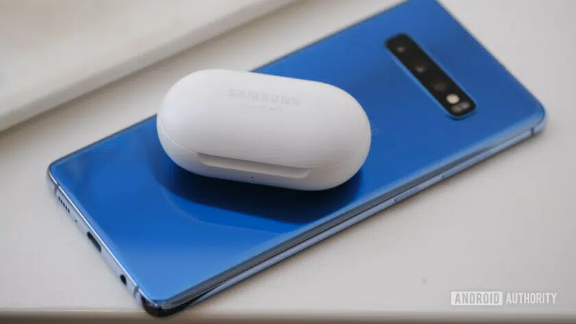 Photo of the backside of a blue Samsung Galaxy S10 Plus with Galaxy Buds on top of it.