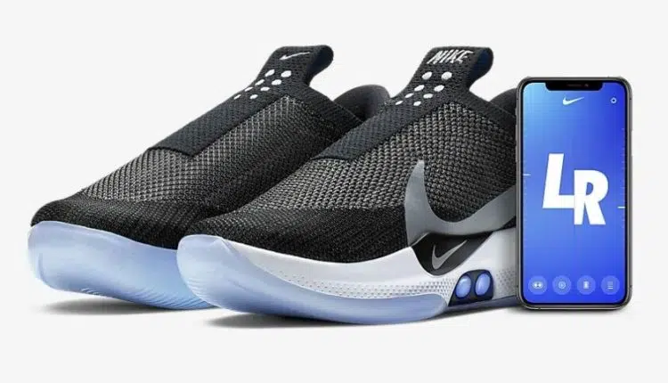 The Nike Adapt BB sneakers with a phone beside them.